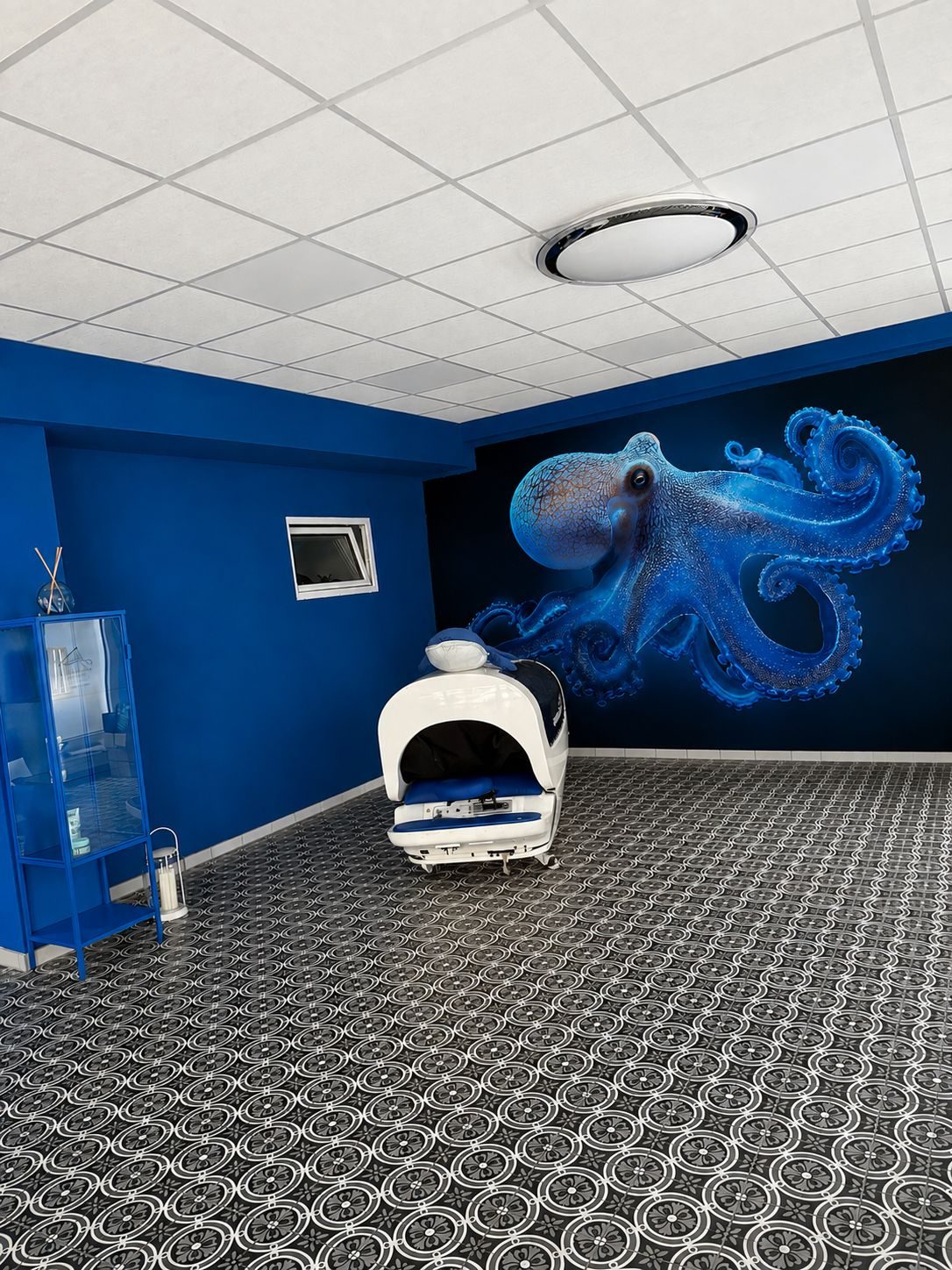 Aqua-Massage-Liege für trockene Hydromassage vor blauem Oktopus-Wandbild