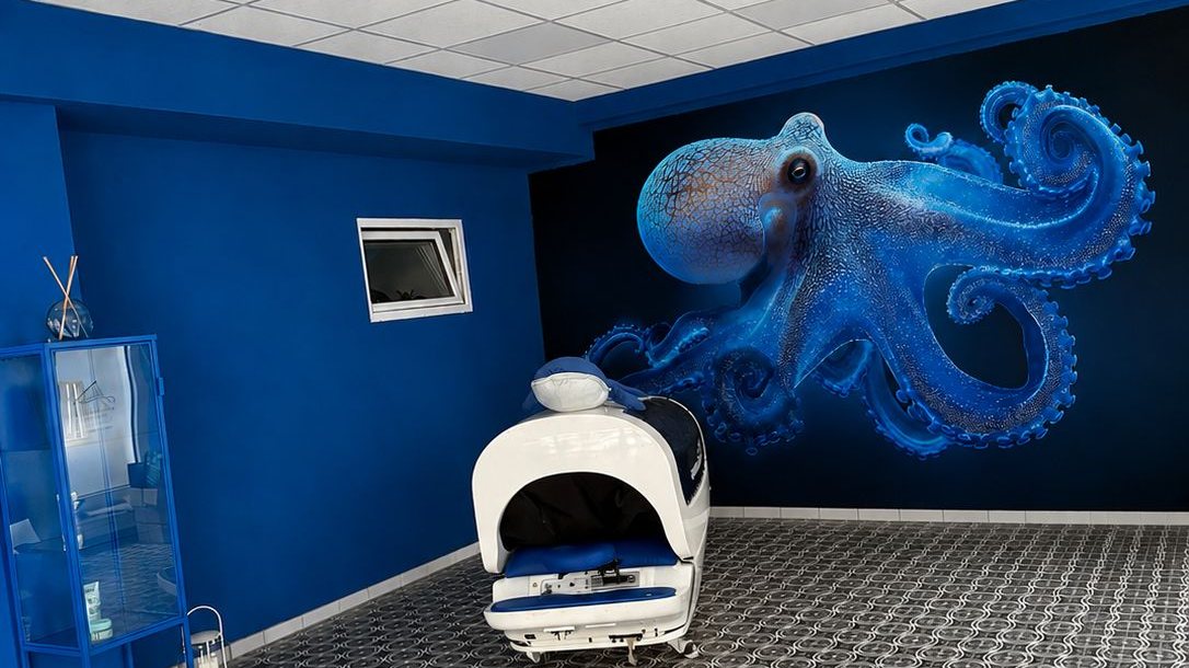 Aqua-Massage-Raum im Salon Aquamassage & Head Spa in Mönchengladbach mit blauem Unterwasser-Wandbild und Hydromassage-Liege